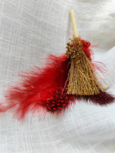 escoba mágica con plumas rojas y cascabel rojo