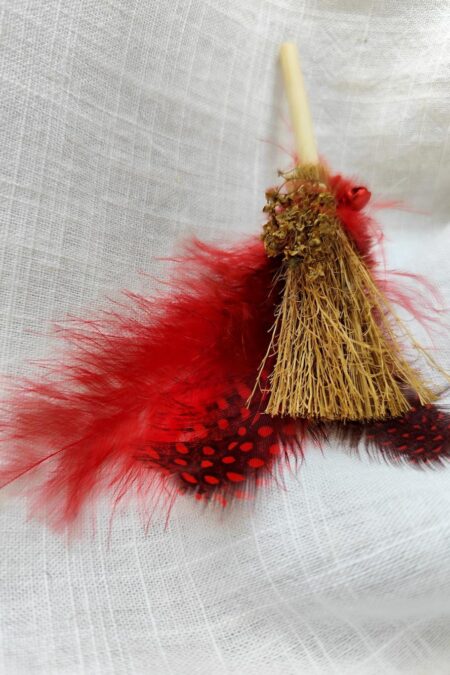escoba mágica con plumas rojas y cascabel rojo